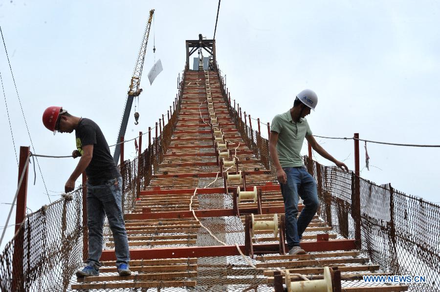 Workers check the guardrail at the construction site of the vitreous bridge above the grand canyon in Zhangjiajie, central China's Hunan Province, June 15, 2015. 