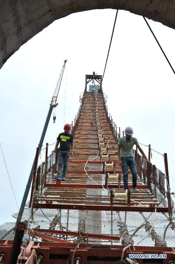 Workers check the guardrail at the construction site of the vitreous bridge above the grand canyon in Zhangjiajie, central China's Hunan Province, June 15, 2015.