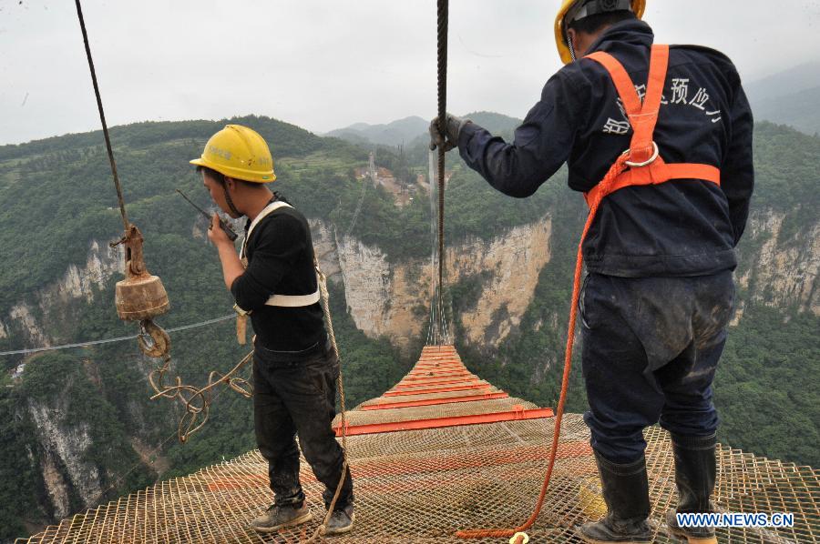 Workers build the vitreous bridge above the grand canyon in Zhangjiajie, central China's Hunan Province, June 15, 2015. 