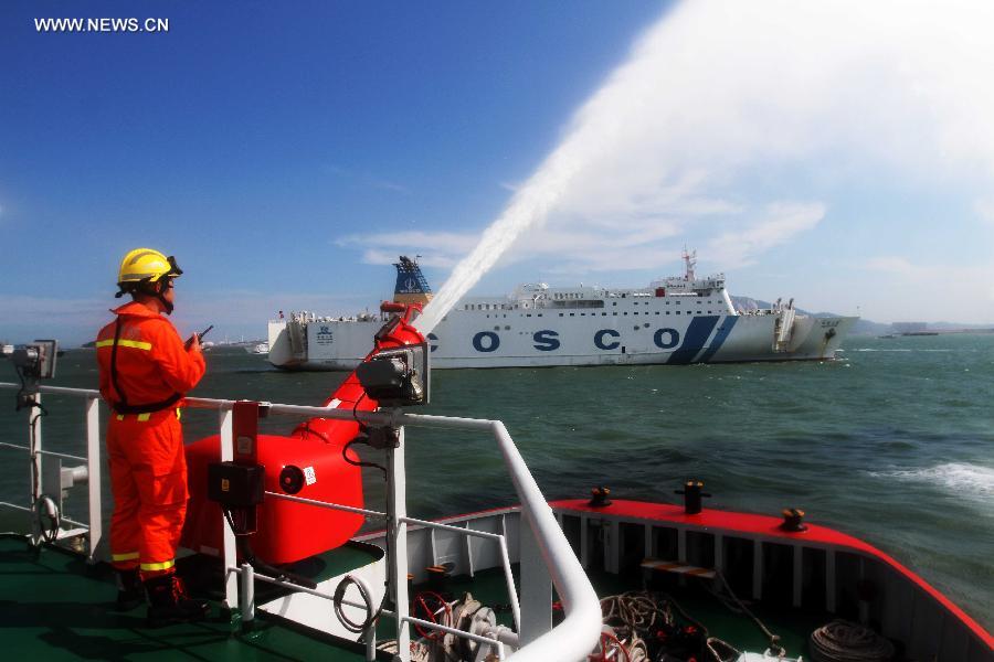 A fireboat sprays water to a passenger vessel during a rescue drill in Xiamen, southeast China's Fujian Province, June 15, 2015.