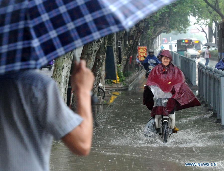 A resident tries to ride past a waterlogged road in Suzhou, east China's Jiangsu Province, June 16, 2015.