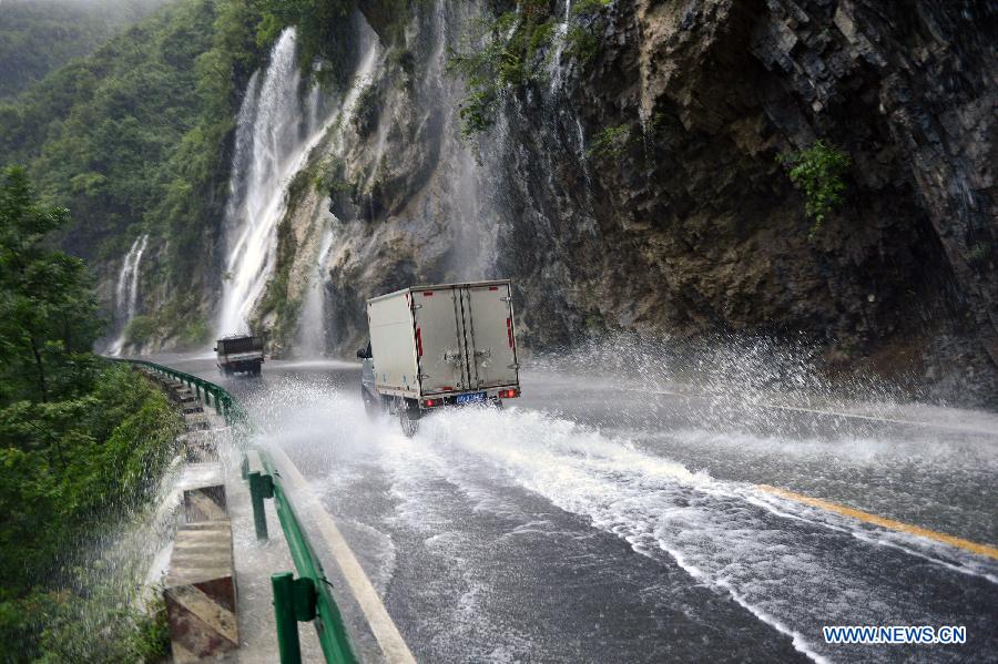 Vehicles run on a flooded road in Gaoluo Town of Xuan'en County, central China's Hubei Province, June 17, 2015.