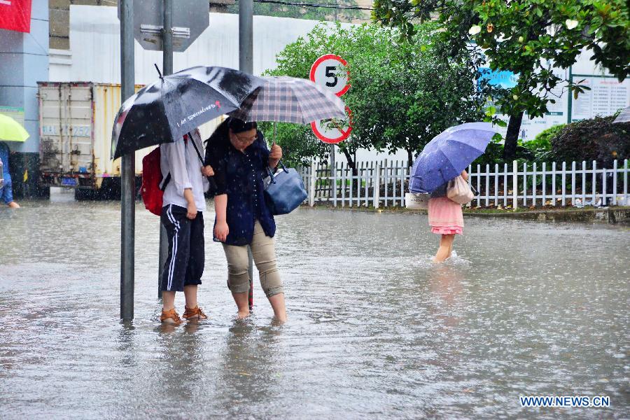 Residents try to walk past a flooded street in Shanghai, east China, June 17, 2015. 