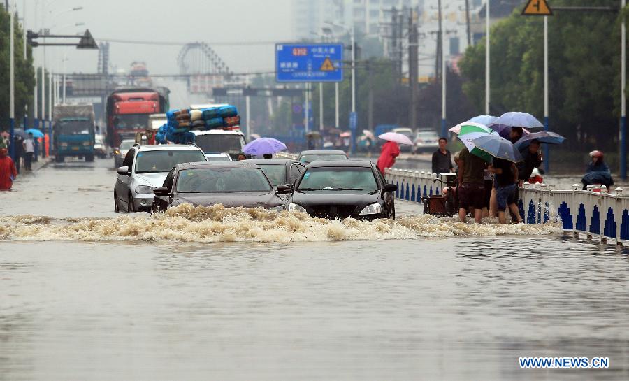 Motorcars try to pass a flooded road in Changzhou, east China's Jiangsu Province, June 17, 2015.