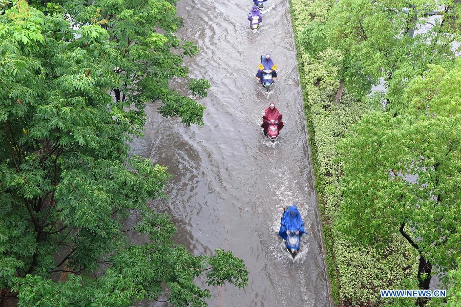 Residents ride motorcycles to pass a flooded road in Wuxi, east China's Jiangsu Province, June 17, 2015.