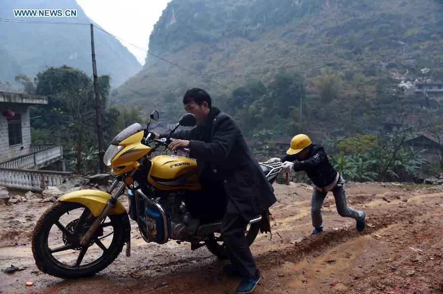 Villagers of Nongyong Village push a motorcycle on a muddy road in Dahua Yao Autonomous County, south China's Guangxi Zhuang Autonomous Region, Feb. 14, 2015. 