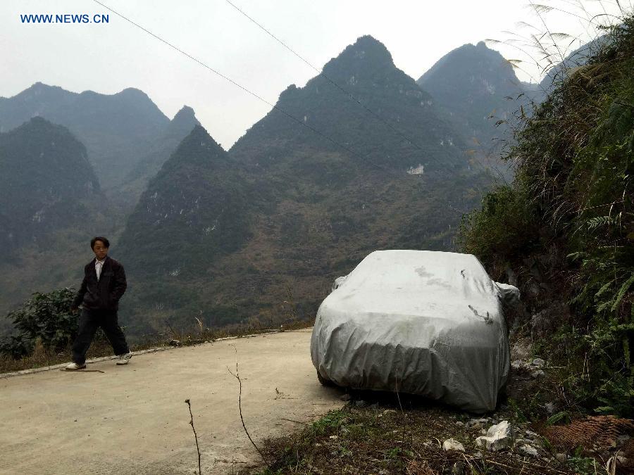 A young man of Nongyong Village returning to his hometown with a car has to park his car at the foot of a hill as no road accessible to Nongyong Village in Dahua Yao Autonomous County, south China's Guangxi Zhuang Autonomous Region, Feb. 13, 2015.