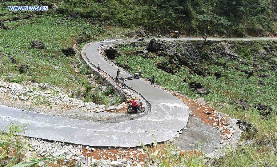 Workers lay a cement road linking Nongyong Village to Nongling Town in Dahua Yao Autonomous County, south China's Guangxi Zhuang Autonomous Region, May 11, 2015. 