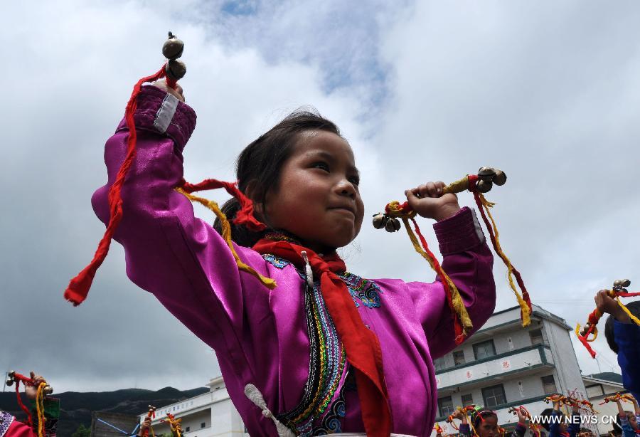 Puipls perform the traditional Yi bell dance at Bandi Elementary School in Bandi Township of Weining County, southwest China's Guizhou Province, July 1, 2015. 