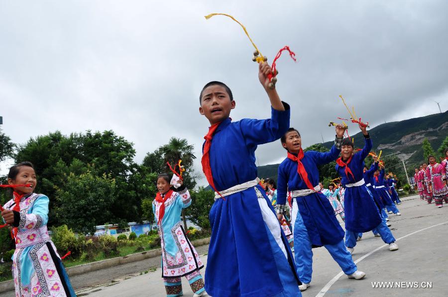 Puipls perform the traditional Yi bell dance at Bandi Elementary School in Bandi Township of Weining County, southwest China's Guizhou Province, July 1, 2015. 