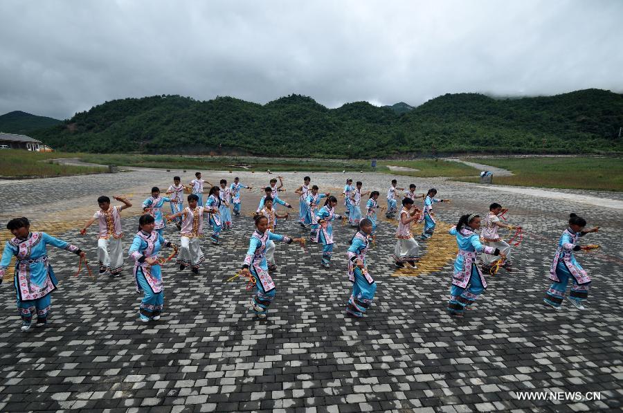 Puipls perform the traditional Yi bell dance at Bandi Elementary School in Bandi Township of Weining County, southwest China's Guizhou Province, July 1, 2015. 