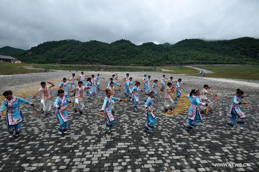 Puipls perform the traditional Yi bell dance at Bandi Elementary School in Bandi Township of Weining County, southwest China's Guizhou Province, July 1, 2015. 