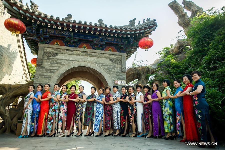 Models present cheong-sam creations during a commonweal activity at the Dahuaishu scenic zone in Hongtong County, north China's Shanxi Province, July 4, 2015. 