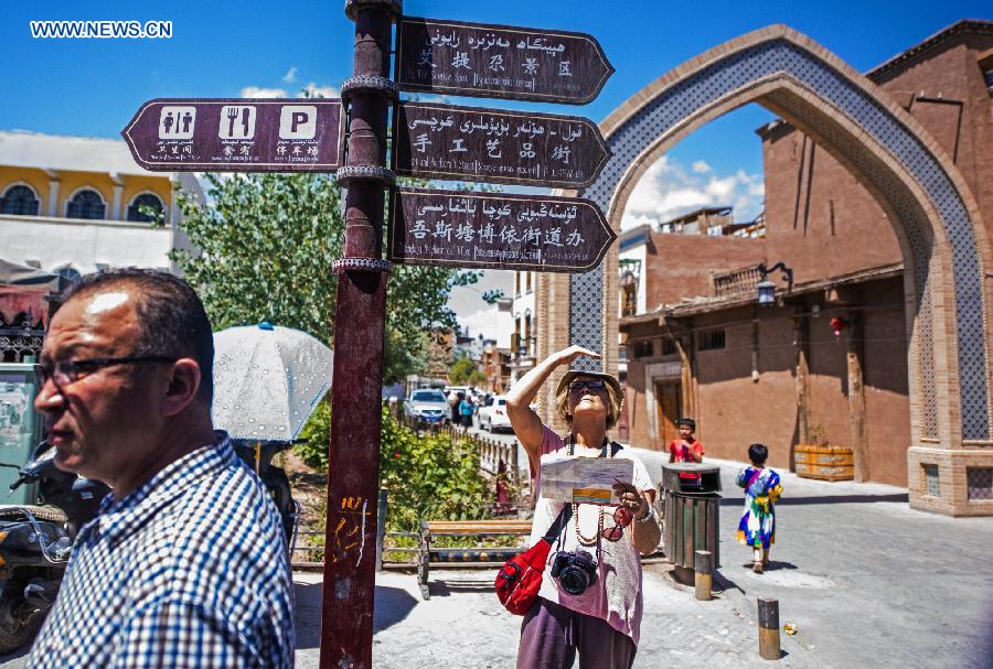 Photo taken on June 8, 2015 shows a foreign tourist in the old town of Kax, northwest China's Xinjiang Uygur Autonomous Region.