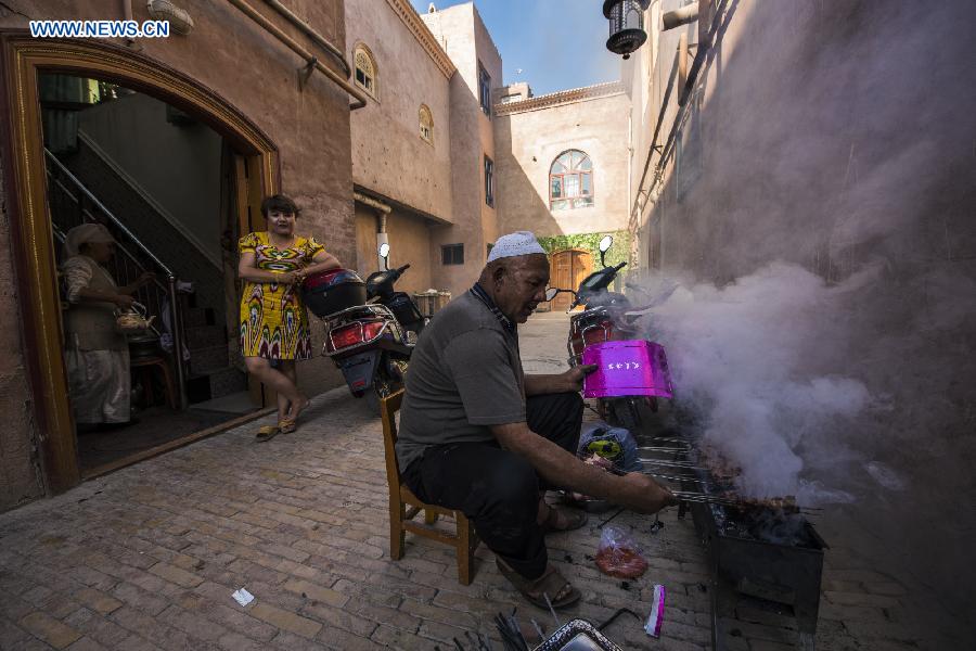 Photo taken on June 7, 2015 shows a resident grilling lamb at the door of his house in the old town of the old town of Kax, northwest China's Xinjiang Uygur Autonomous Region.