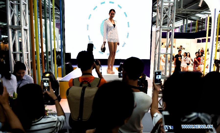 Visitors view a model displaying a creation during the 15th China International Fashion Brand Fair held in Shenzhen, south China, July 9, 2015.