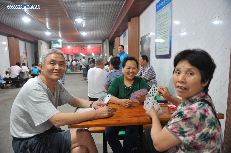 Citizens play cards when cooling off at a bomb shelter in Chongqing, southwest China, July 9, 2015. 