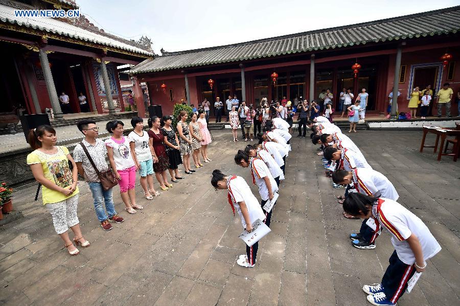 Students bow to their parents at the Confucius classroom in the Confucius temple of Wenchang, south China's Hainan Province, July 10, 2015.