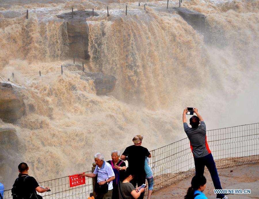 Tourist take photos of Hukou Waterfall on the Yellow River in Linfen, north China's Shanxi Province, July 10, 2015. 