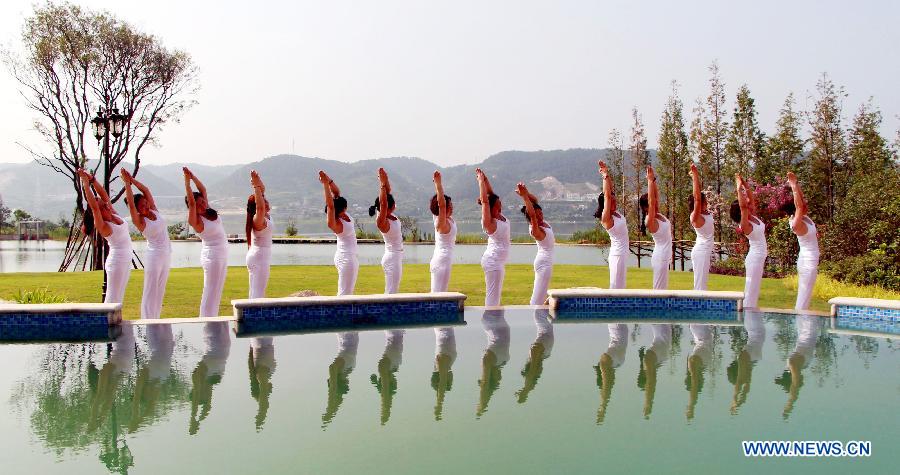 Yoga lovers practise yoga to relax themselves at the bank of Hanjian River in Shiyan, central China's Hubei Province, July 12, 2015.