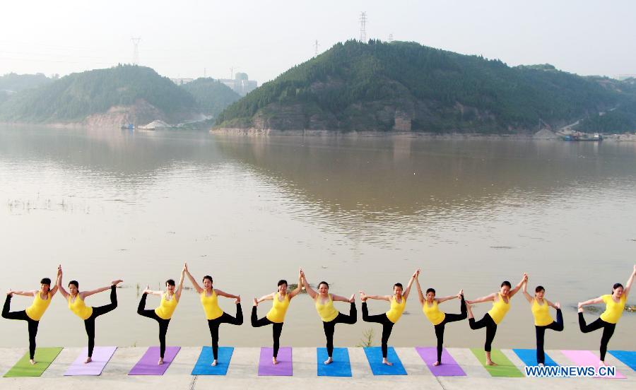 Yoga lovers practise yoga to relax themselves at the bank of Hanjian River in Shiyan, central China's Hubei Province, July 12, 2015. 