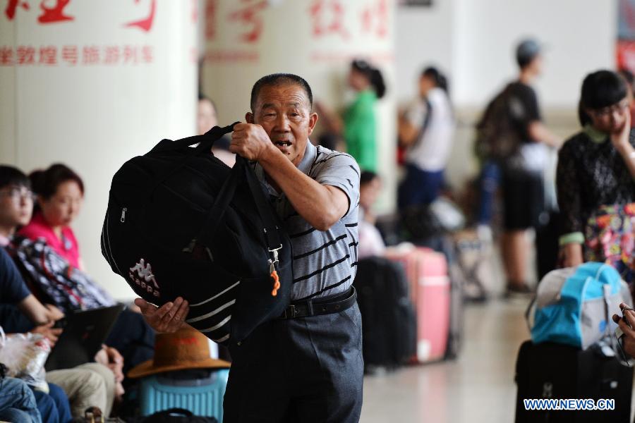 A passenger carrying luggages waits for a train at Lanzhou Railway Station in Lanzhou, capital of northwest China's Gansu Province, July 13, 2015. 