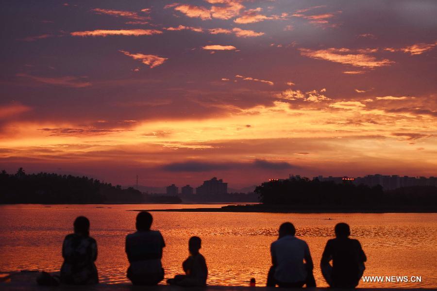 People enjoy sunglow beside the Wanquan River in Qionghai of south China's Hainan Province, July 13, 2015. 