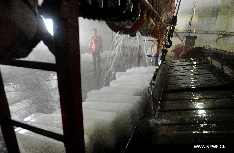 Workers produce ice bricks at a plant in Suzhou City, east China's Jiangsu Province, July 14, 2015. Ice bricks sold well as the temperature climbed up high in Suzhou. 