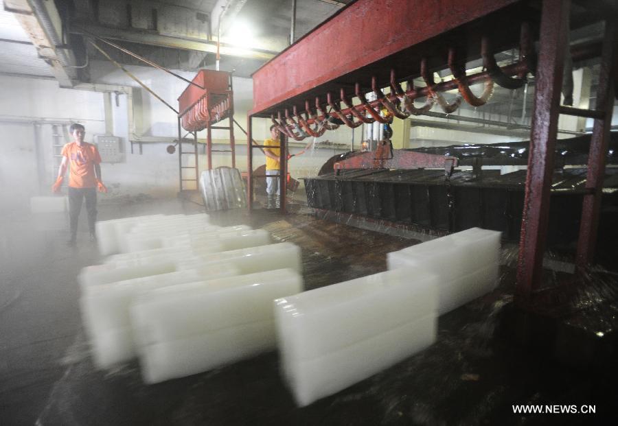 Workers produce ice bricks at a plant in Suzhou City, east China's Jiangsu Province, July 14, 2015. Ice bricks sold well as the temperature climbed up high in Suzhou. 