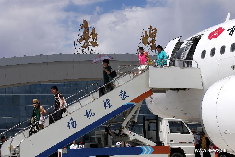 Passengers walk off the plane after the first flight from Qingdao to Dunhuang arrived at Dunhuang Airport in Dunhuang, northwest China's Gansu Province, July 16, 2015. 