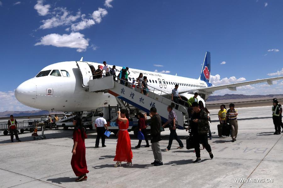 Passengers walk off the plane after the first flight from Qingdao to Dunhuang arrived at Dunhuang Airport in Dunhuang, northwest China's Gansu Province, July 16, 2015. 