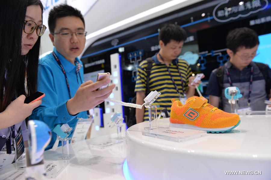 People take photos of a children's shoe which has the function of trace during the Mobile World Congress Shanghai in Shanghai, east China, July 17, 2015. 