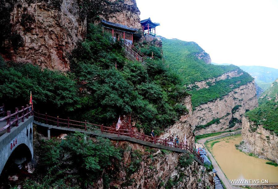 Tourists visit ancient Taoist temples built on the cliff in Sanggan River canyon in Xuanhua County, north China's Hebei Province, July 20, 2015.