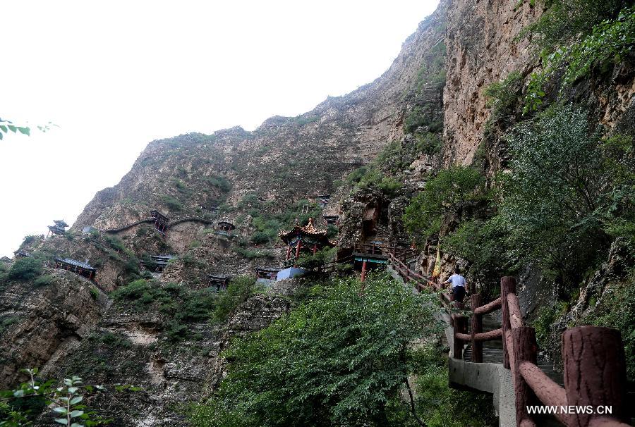 Tourists visit ancient Taoist temples built on the cliff in Sanggan River canyon in Xuanhua County, north China's Hebei Province, July 20, 2015. 