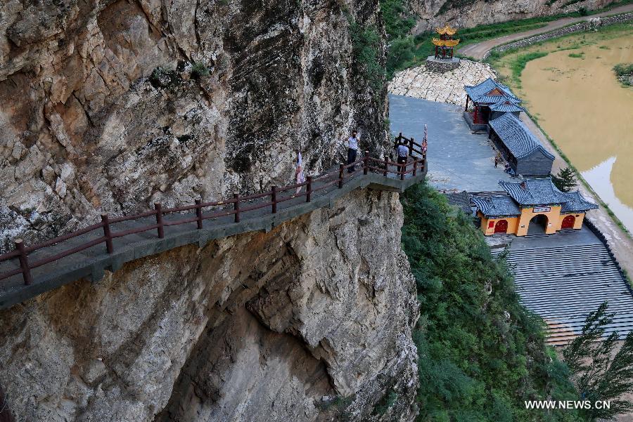 Tourists visit ancient Taoist temples built on the cliff in Sanggan River canyon in Xuanhua County, north China's Hebei Province, July 20, 2015.