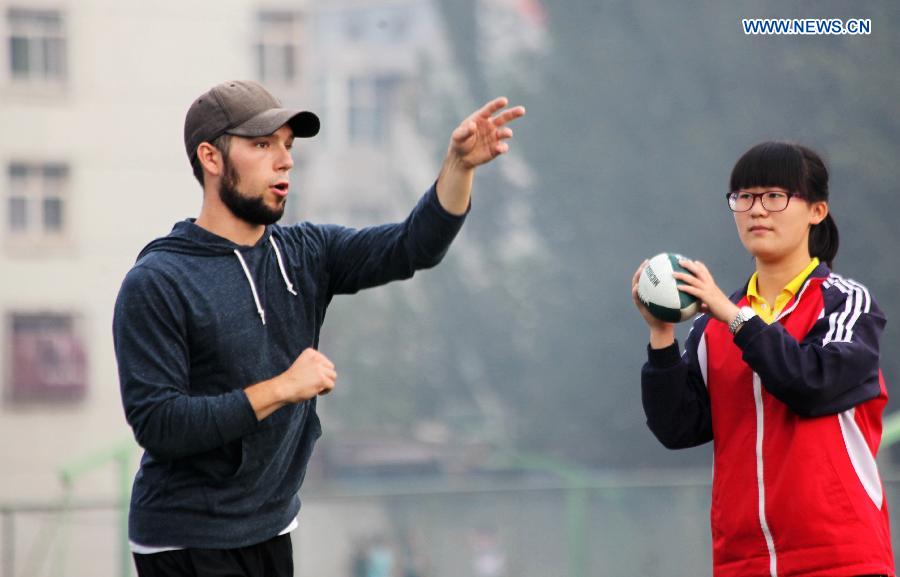 Eric, a student of Michigan State University, teaches a student football moves at Xuanhua No. 4 middle school in Zhangjiakou, north China's Hebei Province, July 21, 2015. 