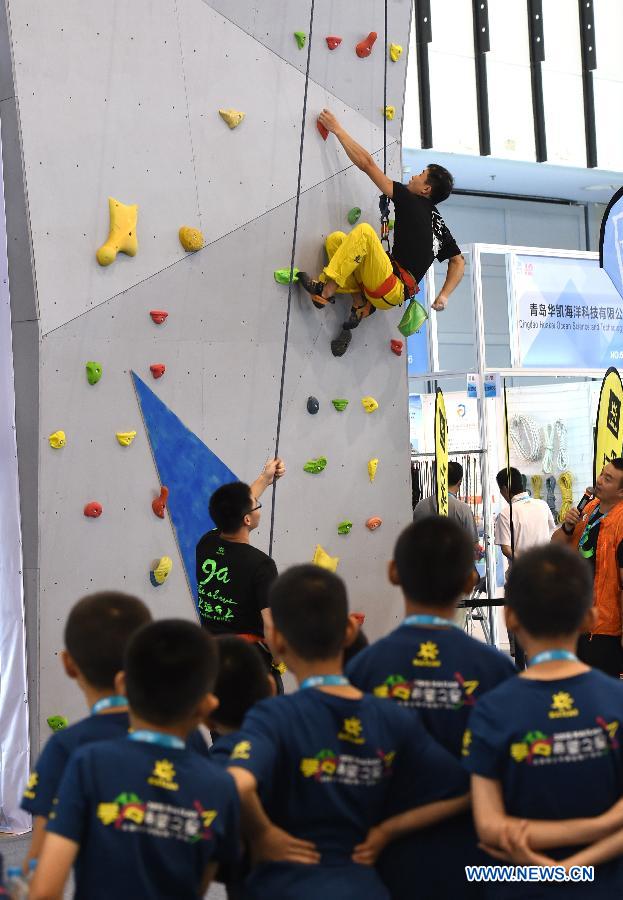 A man demonstrates dry tooling skills for teenagers during the Asia Outdoor Trade Show 2015 in Nanjing, capital of east China's Jiangsu Province, July 23, 2015. 