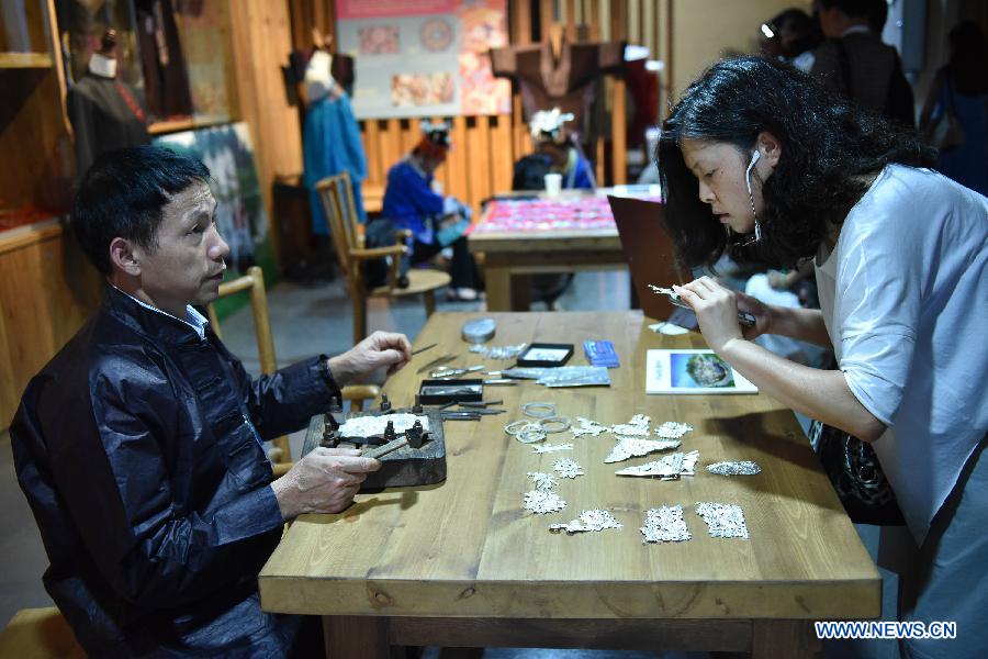 A visitor views silver ornaments of Miao ethnic group during a culture expo in Guiyang, capital of southwest China's Guizhou Province, July 24, 2015. 