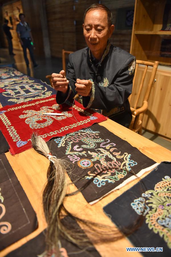 A craftsman shows processes of making a horse-tail embroidery during a culture expo in Guiyang, capital of southwest China's Guizhou Province, July 24, 2015.