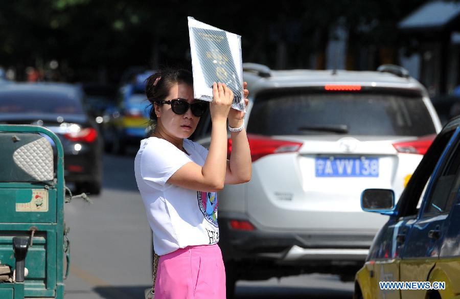 A woman uses a bag to shield from the scorching sun in Yinchuan, capital of northwest China's Ningxia Hui Autonomous Region, July 24, 2015. 