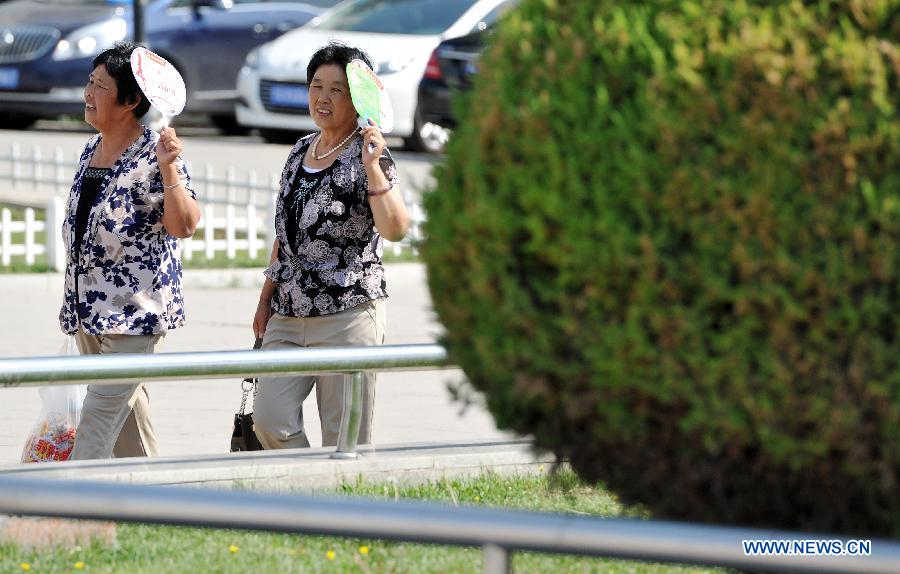 People walk with fans to shield from the scorching sun in Yinchuan, capital of northwest China's Ningxia Hui Autonomous Region, July 24, 2015. 