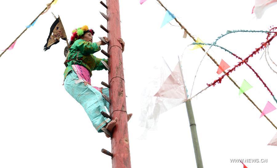 An inheritor of Yang opera performs 'climbing mountain of knife' at a fair in Gulong village, southwest China's Guizhou Province, July 25, 2015. Yang opera, a branch of Nuo opera, is listed in the provincial intangible cultural heritages.(Xinhua/Wu Rubo) 