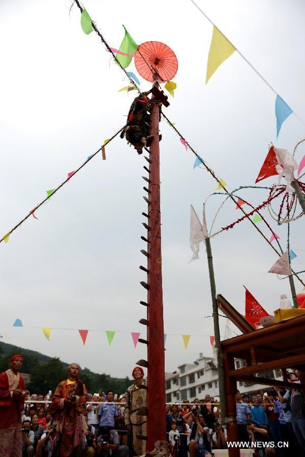 An inheritor of Yang opera performs 'climbing mountain of knife' at a fair in Gulong village, southwest China's Guizhou Province, July 25, 2015. Yang opera, a branch of Nuo opera, is listed in the provincial intangible cultural heritages.(Xinhua/Wu Rubo) 