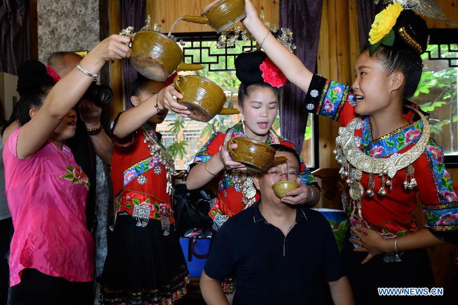 Villagers of Miao ethnic group propose a toast to a tourist at Xijiang Qianhu Miao Village in Leishan County, southwest China's Guizhou Province, July 29, 2015. The village with more than 1,000 wooden stilted houses attracted a large number of tourists in the summer travel season. (Xinhua/Qiao Qiming) 