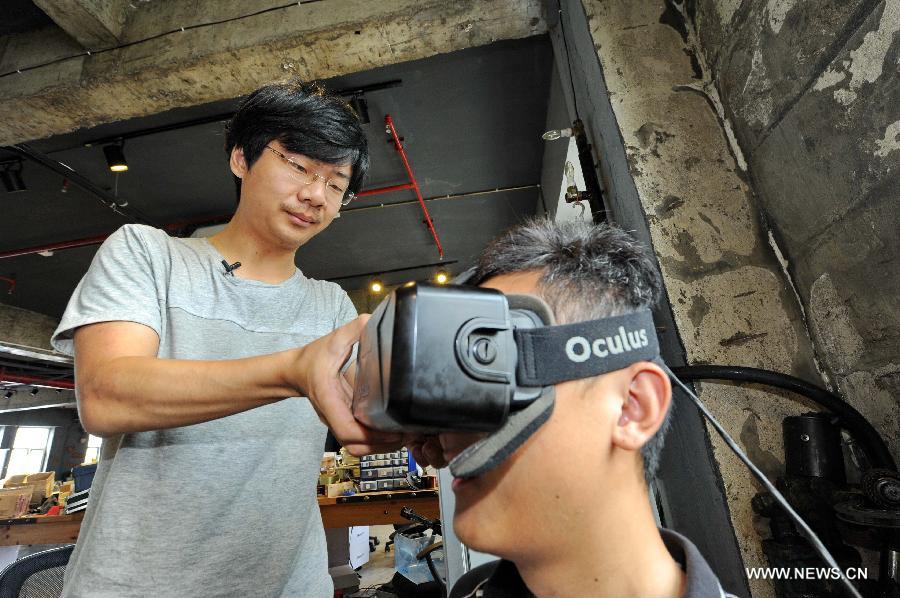 Hou Xiaoye (L) helps a man put on a wearable virtual reality headset at the the Baidu Pioneer Park in Changchun, capital of northeast China's Jilin Province, July 30, 2015. Graduated from Jilin University, Gao Hua and Hou Xiaoye are both enthusiasts in science and technology. Getting bored with average work, they founded their geek studio which undertakes innovation of gadgets such as 3D printers, drones and wearable virtual reality headsets that they believe can change people's everyday life. (Xinhua/Zhang Nan) 