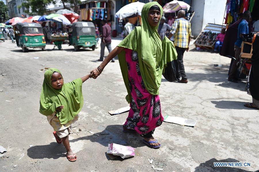 A woman walks inside a market area with a child in Mogadishu, Somalia, July 30, 2015.