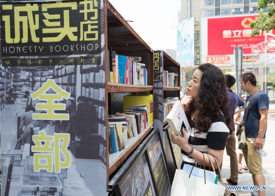 People select books at the Honesty Bookshop in Nanjing, capital of east China's Jiangsu Province, July 28, 2015. The bookshop has no cashier desk and no working staff. Customers purchase books by dropping money into a money box on their own free will. The organizer opened the bookshop to raise the awareness of honesty. (Xinhua/Su Yang)