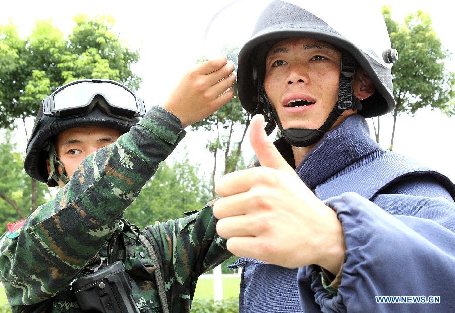 Zhang Yanbiao(R), an Explosive Ordance Disposal(EDO) police, wears a 25-kilogram anti-expolsion suit during a training in east China's Shanghai Municipality, July 30, 2015. EDO police of Shanghai armed police unit continued their training as the heat wave scorched Shanghai. (Xinhua/Chen Fei) 