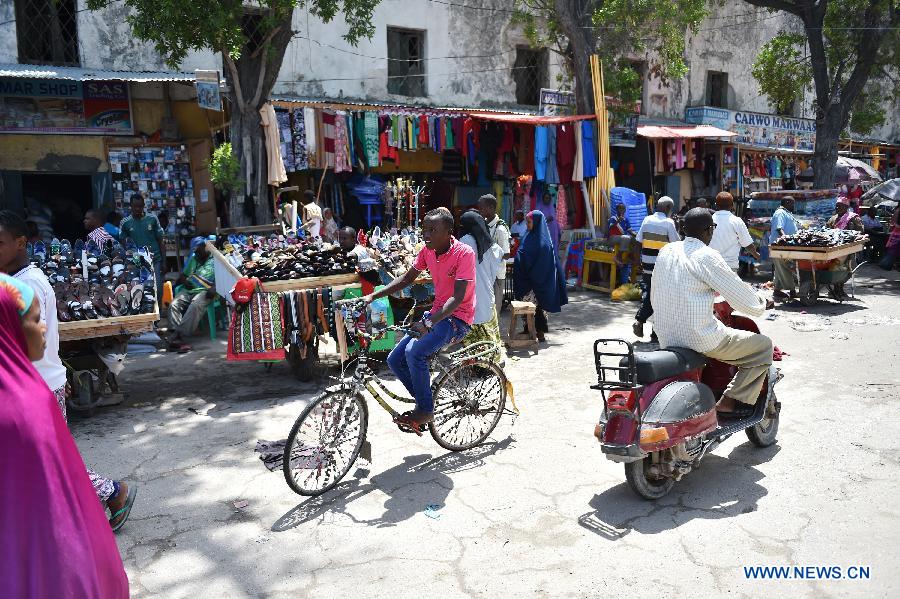 People ride past a market along a street in Mogadishu, Somalia, July 30, 2015.