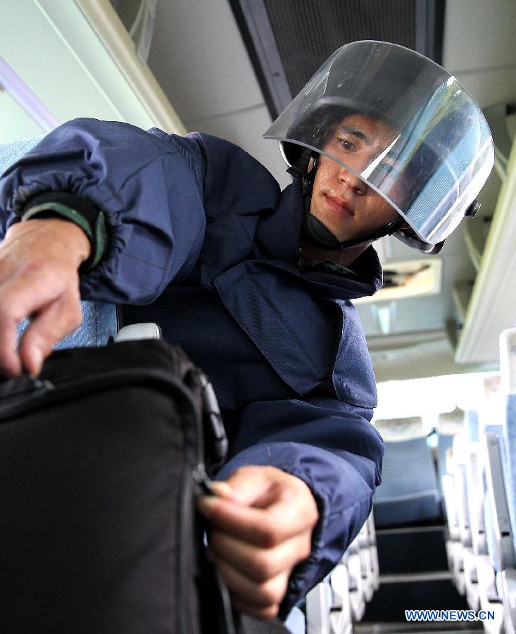 Xie Liuxiang, an Explosive Ordance Disposal(EDO) police, practices to defuse a bomb safely in a bus during a training in east China's Shanghai Municipality, July 30, 2015. EDO police of Shanghai armed police unit continued their training as the heat wave scorched Shanghai. (Xinhua/Chen Fei) 